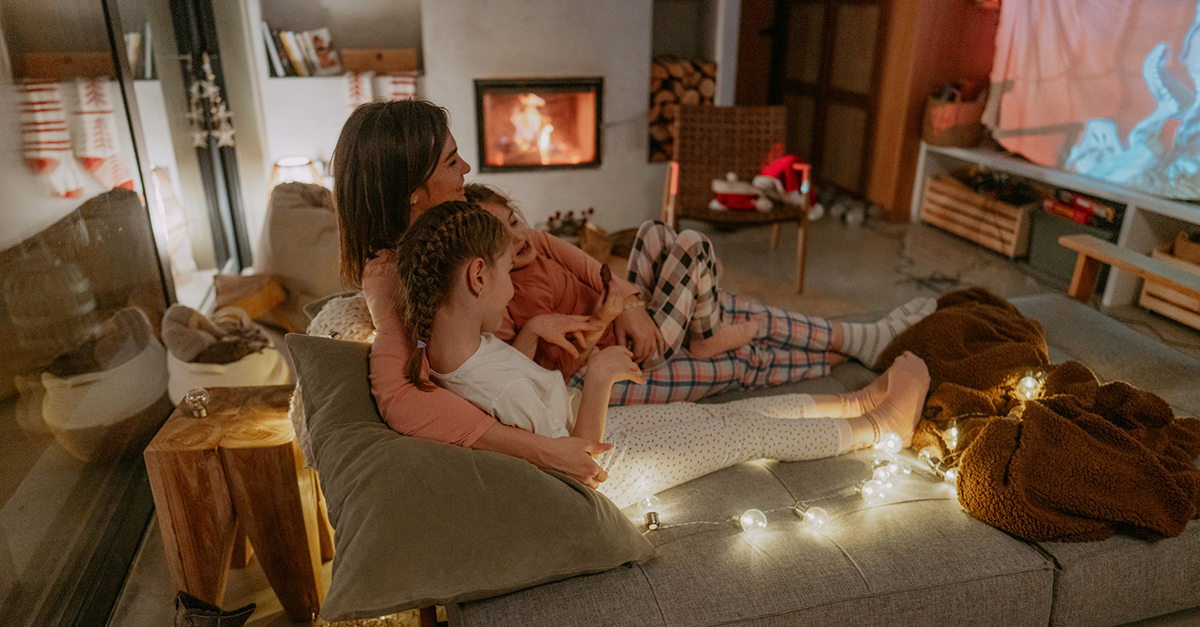 A mom and her daughters watching movies on a big screen