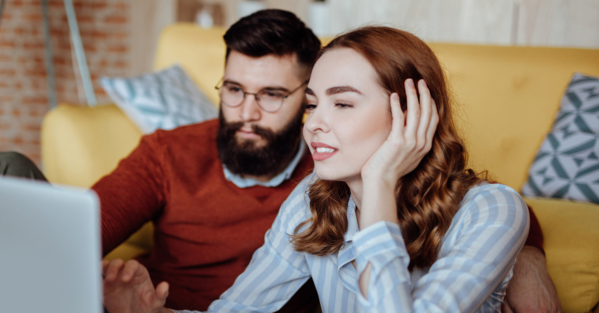 A young couple shops for homes on a laptop